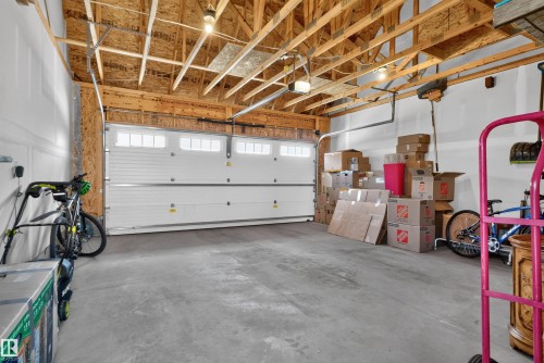 Exposed wood beam ceiling, concrete flooring, and a white garage door with upper window inserts - 319 Desrochers Boulevard Sw, Edmonton, AB 
