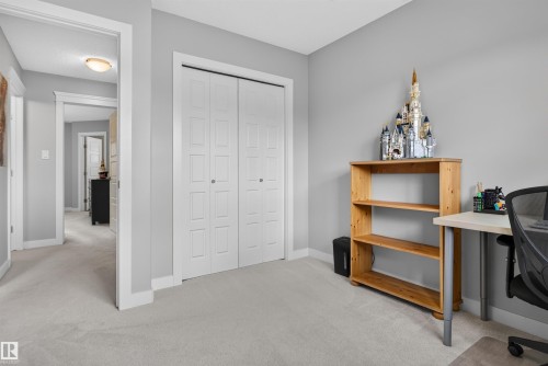 Neutral tone wall paint, light-colored carpeting, white trim, and bi-fold closet doors - 319 Desrochers Boulevard Sw, Edmonton, AB 