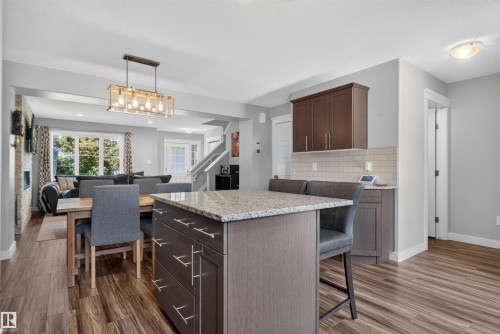 Kitchen island with a light-toned countertop, wood-finish flooring, and white subway tile backsplash - 319 Desrochers Boulevard Sw, Edmonton, AB 