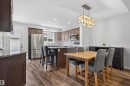Open-concept kitchen and dining area featuring wood-finish flooring, recessed lighting, and a linear chandelier - 319 Desrochers Boulevard Sw, Edmonton, AB 