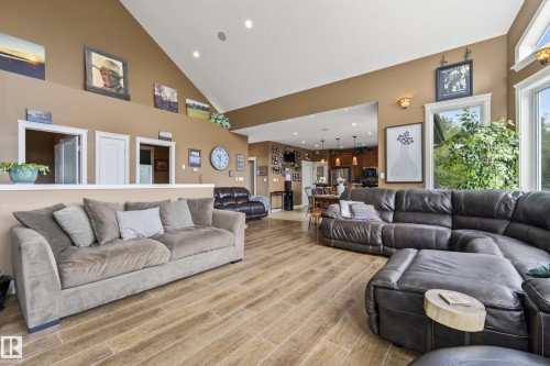 Spacious living area featuring vaulted ceilings, wood-finish flooring, recessed lighting, large windows, and a partial wall separating spaces - 48109 Rr 155, Rural Beaver County, AB - Indoor Photo Showing Living Room