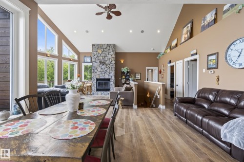 Open-concept living area featuring a vaulted ceiling, wood-finish flooring, and a stone-faced fireplace - 48109 Rr 155, Rural Beaver County, AB - Indoor With Fireplace