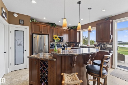 Kitchen featuring rich wood cabinetry and a tiered island with an integrated wine rack - 48109 Rr 155, Rural Beaver County, AB - Indoor Photo Showing Kitchen With Upgraded Kitchen