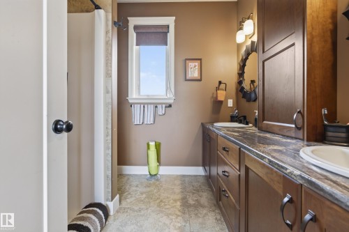 Bathroom featuring a dual vanity with undermount sinks, dark wood cabinetry, and a stone-finish countertop - 48109 Rr 155, Rural Beaver County, AB - Indoor Photo Showing Bathroom