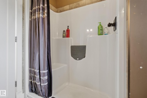 White fiberglass shower enclosure with an integrated seating bench and storage shelf, featuring a matte black shower fixture - 48109 Rr 155, Rural Beaver County, AB - Indoor Photo Showing Bathroom