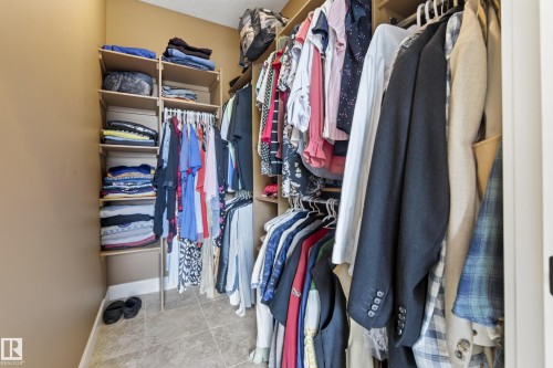 Walk-in closet featuring extensive built-in shelving, multiple hanging rods, and neutral-toned tile flooring - 48109 Rr 155, Rural Beaver County, AB - Indoor With Storage
