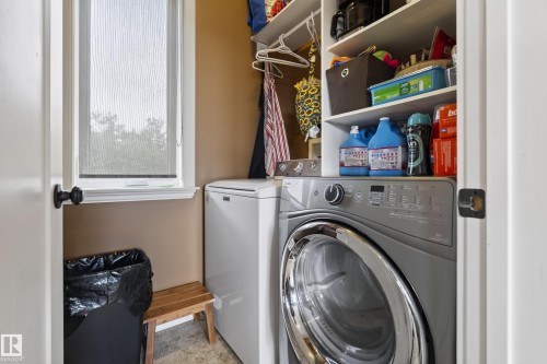 Dedicated laundry area featuring built-in shelving, a window with privacy blind, and durable flooring - 48109 Rr 155, Rural Beaver County, AB - Indoor Photo Showing Laundry Room