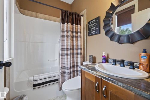 Bathroom vanity with an oval undermount sink, dark countertop, and matte black faucet - 48109 Rr 155, Rural Beaver County, AB - Indoor Photo Showing Bathroom