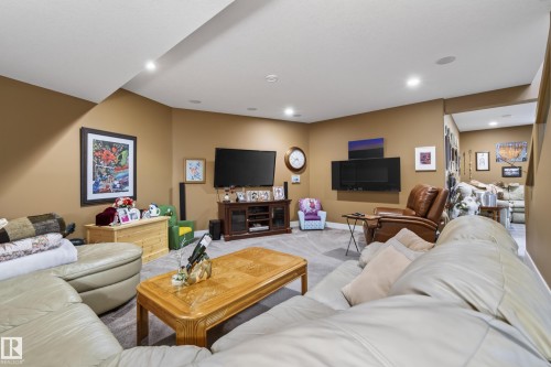 Spacious recreation room featuring recessed lighting, light-toned carpeting, a wall-mounted electric fireplace, a media console, and a clear entryway to an additional room - 48109 Rr 155, Rural Beaver County, AB - Indoor Photo Showing Other Room