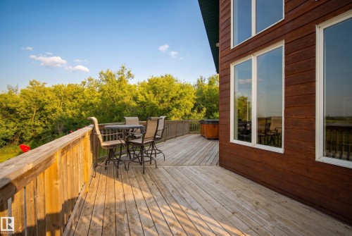 Spacious outdoor deck featuring natural wood flooring and railing, a built-in hot tub, and direct access to interior spaces through large windows - 48109 Rr 155, Rural Beaver County, AB - Outdoor With Deck Patio Veranda With Exterior