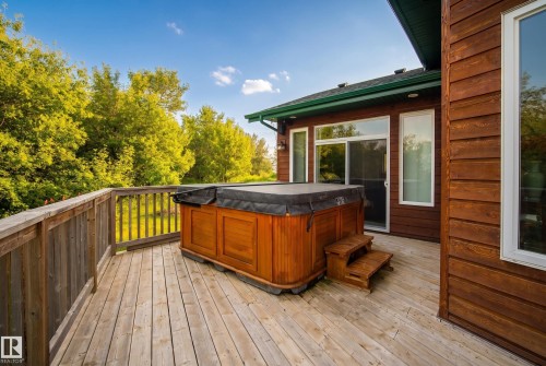 Expansive wood deck featuring a covered hot tub, wood railing, and direct access to the home via a sliding glass door - 48109 Rr 155, Rural Beaver County, AB - Outdoor With Deck Patio Veranda With Exterior