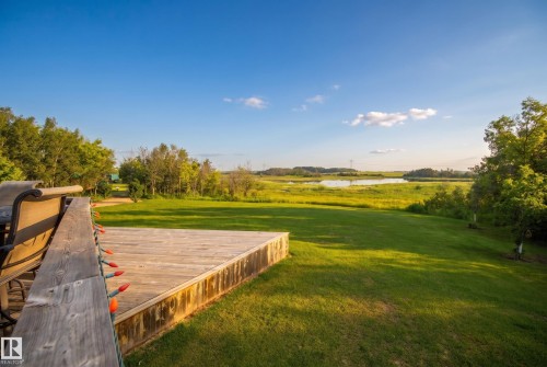 Expansive wood deck overlooking a manicured lawn, surrounded by lush trees and a body of water with marshland beyond - 48109 Rr 155, Rural Beaver County, AB - Outdoor With View