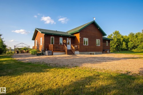 Exterior featuring wood siding, a dark green roof, multiple windows, and a raised wood deck with railings - 48109 Rr 155, Rural Beaver County, AB - Outdoor