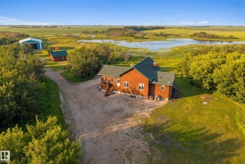 Expansive property featuring a red-sided residence with green roofing, a large detached metal building, and two additional outbuildings - 48109 Rr 155, Rural Beaver County, AB - Outdoor With View