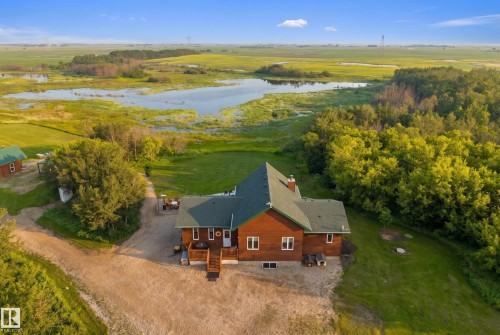 Expansive rural property featuring a large residence with wood siding and a green shingled roof, surrounded by mature trees and natural wetlands - 48109 Rr 155, Rural Beaver County, AB - Outdoor With View