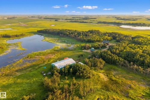 Expansive property featuring a tranquil lake, lush green fields, mature tree lines, and a residential structure - 48109 Rr 155, Rural Beaver County, AB - Outdoor With View