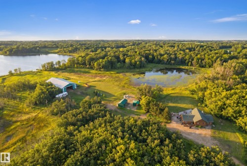 Expansive property featuring a sizable body of water, dense surrounding foliage, and multiple structures - 48109 Rr 155, Rural Beaver County, AB - Outdoor With Body Of Water With View