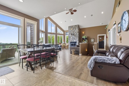 Spacious great room featuring vaulted ceilings, a stone fireplace, wood-finish flooring, recessed lighting, and expansive windows - 48109 Rr 155, Rural Beaver County, AB - Indoor With Fireplace