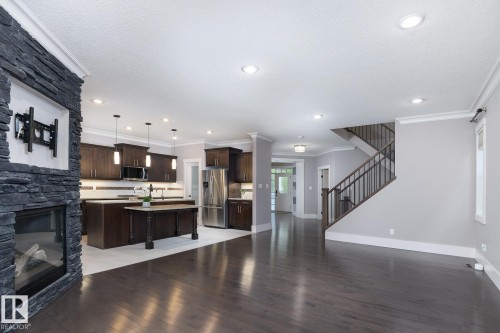 Dark wood-finish flooring with a stone-clad fireplace - 886 Armitage Wynd Sw, Edmonton, AB 