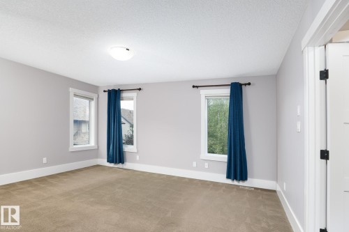 Carpeted room with light gray walls, white trim, and two windows - 886 Armitage Wynd Sw, Edmonton, AB 