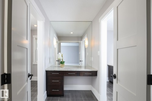 Built-in vanity with dark wood-finish cabinetry, light-toned countertop, and recessed lighting - 886 Armitage Wynd Sw, Edmonton, AB 