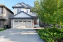 Two-story residence featuring a prominent garage, a concrete driveway, and stone facade accents - 886 Armitage Wynd Sw, Edmonton, AB 