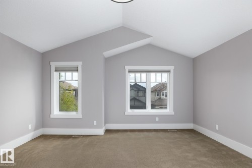 Vaulted ceilings, two windows with white trim, and neutral carpeting - 886 Armitage Wynd Sw, Edmonton, AB 
