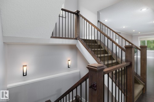 Staircase featuring wood-finish railings with black balusters, carpeted treads, and recessed lighting - 886 Armitage Wynd Sw, Edmonton, AB 