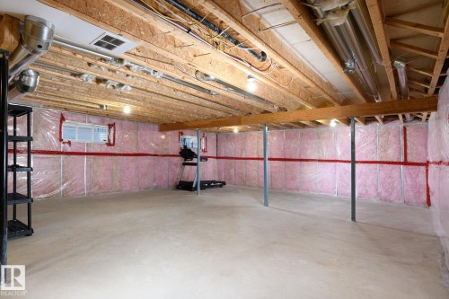 Expansive unfinished basement with exposed wood joists, insulated walls, concrete flooring, and multiple support beams - 886 Armitage Wynd Sw, Edmonton, AB 