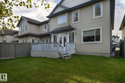 Exterior with siding, multiple windows, a rear deck with railings, and a grassy yard - 886 Armitage Wynd Sw, Edmonton, AB 