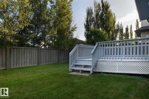 Expansive lawn area, private wood fencing, multi-level wood deck, lattice skirting, and mature trees - 886 Armitage Wynd Sw, Edmonton, AB 