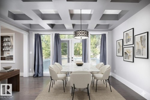Coffered ceiling with recessed lighting, dark wood-finish flooring, French doors, built-in display shelving, and a decorative pendant light fixture - 886 Armitage Wynd Sw, Edmonton, AB 