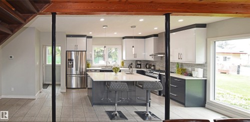 Updated kitchen featuring an island with seating, stainless steel appliances, and dual-tone cabinetry - 9657 68A Street Nw, Edmonton, AB 