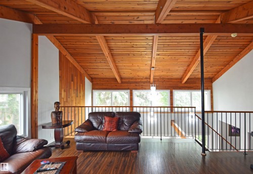 Vaulted wood-plank ceiling with exposed beams, wood-finish flooring, interior balcony with metal railing, and multiple windows - 9657 68A Street Nw, Edmonton, AB 