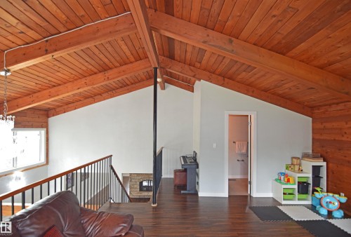 Vaulted wood-paneled ceiling with exposed beams, wood-finish flooring, and a fireplace with stone surround - 9657 68A Street Nw, Edmonton, AB 