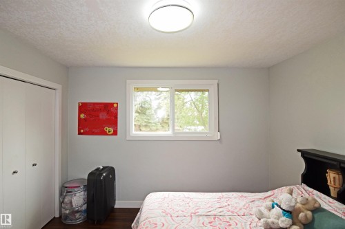 Light gray walls, white trim, wood-finish flooring, white bi-fold closet doors, and an overhead flush-mount light fixture - 9657 68A Street Nw, Edmonton, AB 