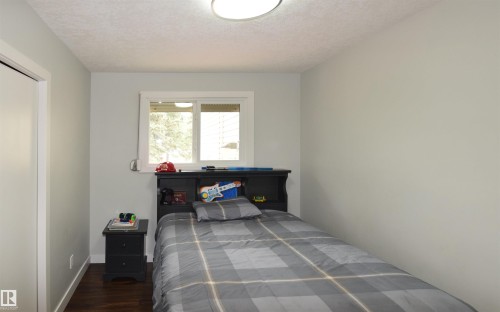 Wood-finish flooring, white trim, and a built-in closet with a solid white door - 9657 68A Street Nw, Edmonton, AB 