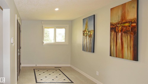 Recessed lighting illuminates the entryway, featuring a tiled floor with a decorative inlay - 9657 68A Street Nw, Edmonton, AB 