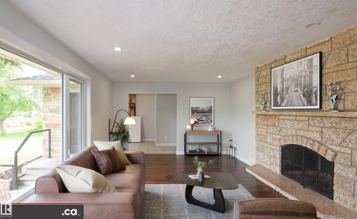 Stone-clad fireplace with hearth, wood-finish flooring, recessed lighting, and sliding glass door - 9657 68A Street Nw, Edmonton, AB 