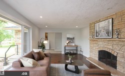 Stone-clad fireplace with hearth, wood-finish flooring, recessed lighting, and sliding glass door - 