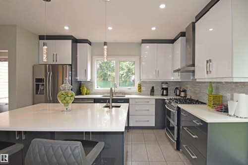 Contemporary kitchen featuring an expansive island, white countertops, two-tone cabinetry, stainless steel appliances, and recessed lighting - 9657 68A Street Nw, Edmonton, AB 