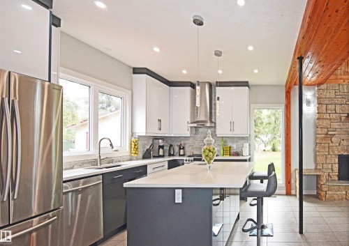 Modern kitchen featuring stainless steel appliances, a center island with countertop seating, white and gray cabinetry, a tile backsplash, and recessed lighting - 9657 68A Street Nw, Edmonton, AB 