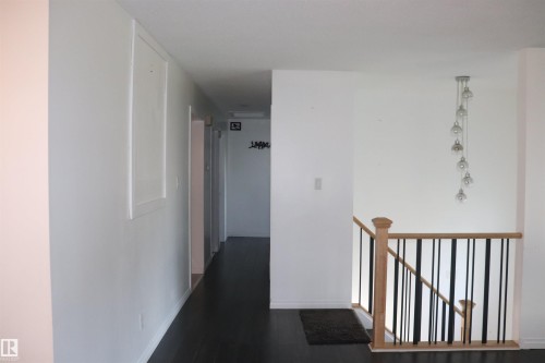 Dark wood-finish flooring, white walls, and a multi-pendant light fixture illuminate the interior space - 8828 151 Avenue Northwest, Edmonton, AB 