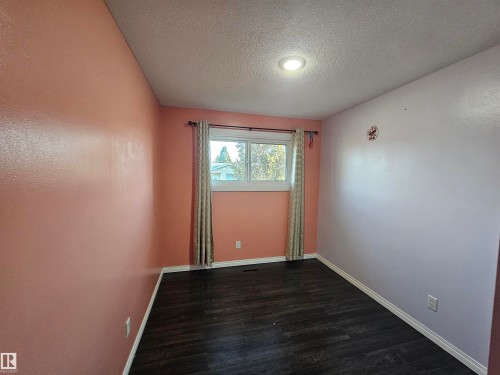 Dark wood-finish flooring, recessed ceiling lighting, window with white trim, white baseboards - 8828 151 Avenue Northwest, Edmonton, AB 