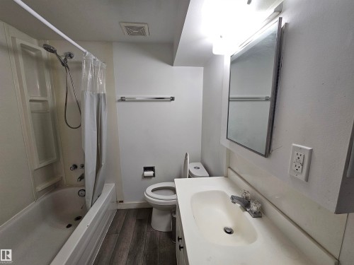 Full bathroom featuring a shower/tub combination, vanity with integrated sink, and wood-finish flooring - 8828 151 Avenue Northwest, Edmonton, AB 