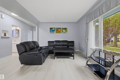 Light wood-finish flooring, large window with upper valance, recessed wall niche, and light gray wall color - 13024 Sherbrooke Avenue Nw, Edmonton, AB 