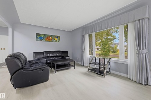 Bay window with window treatments, light wood-finish flooring, and built-in white cabinetry with gold-tone hardware - 13024 Sherbrooke Avenue Nw, Edmonton, AB 