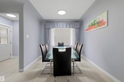 Recessed ceiling with an overhead light fixture, light-toned wood-finish flooring, and a white interior door with frosted glass panels - 