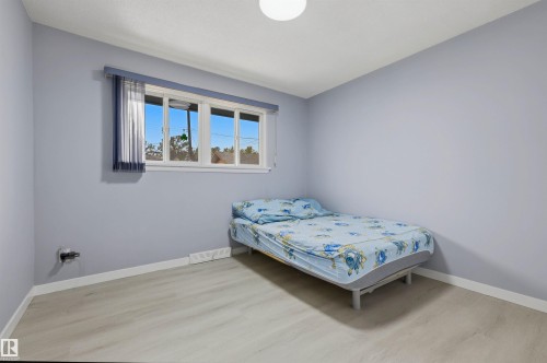 Light wood-finish flooring, white trim, and a window with a sheer and solid blue curtain - 13024 Sherbrooke Avenue Nw, Edmonton, AB 