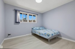 Light wood-finish flooring, white trim, and a window with a sheer and solid blue curtain - 